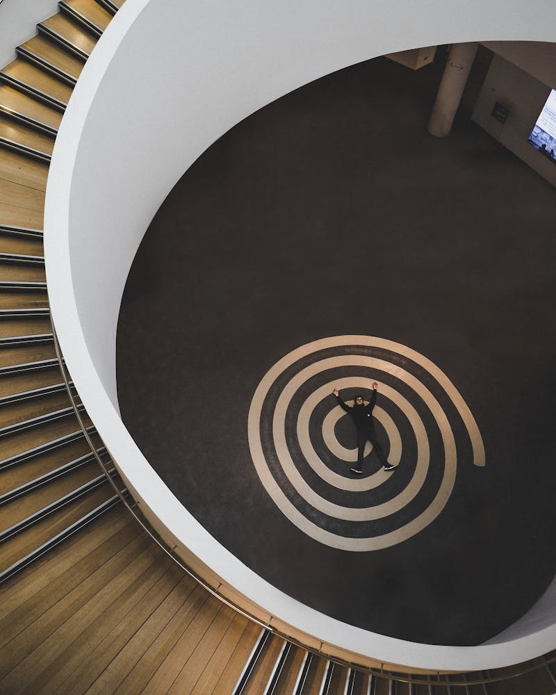 a man lying at the bottom of a spiral stair case