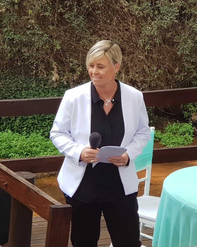 Anita speaking at wedding with microphone in hand.