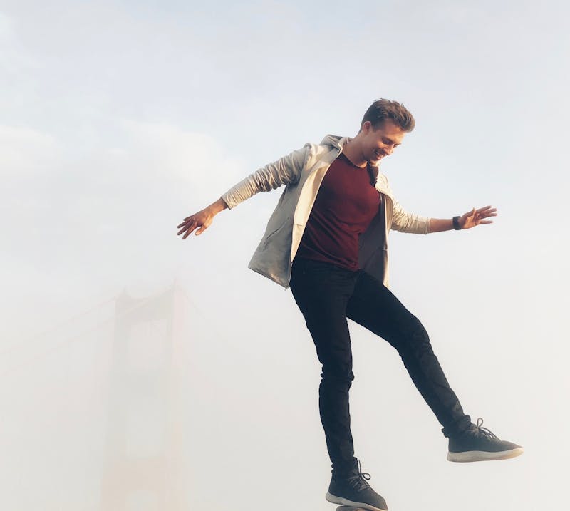 a young man balancing on one leg with a smile on his face