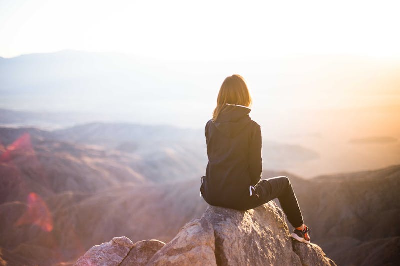 Girl sitting on rock looking into distance.
