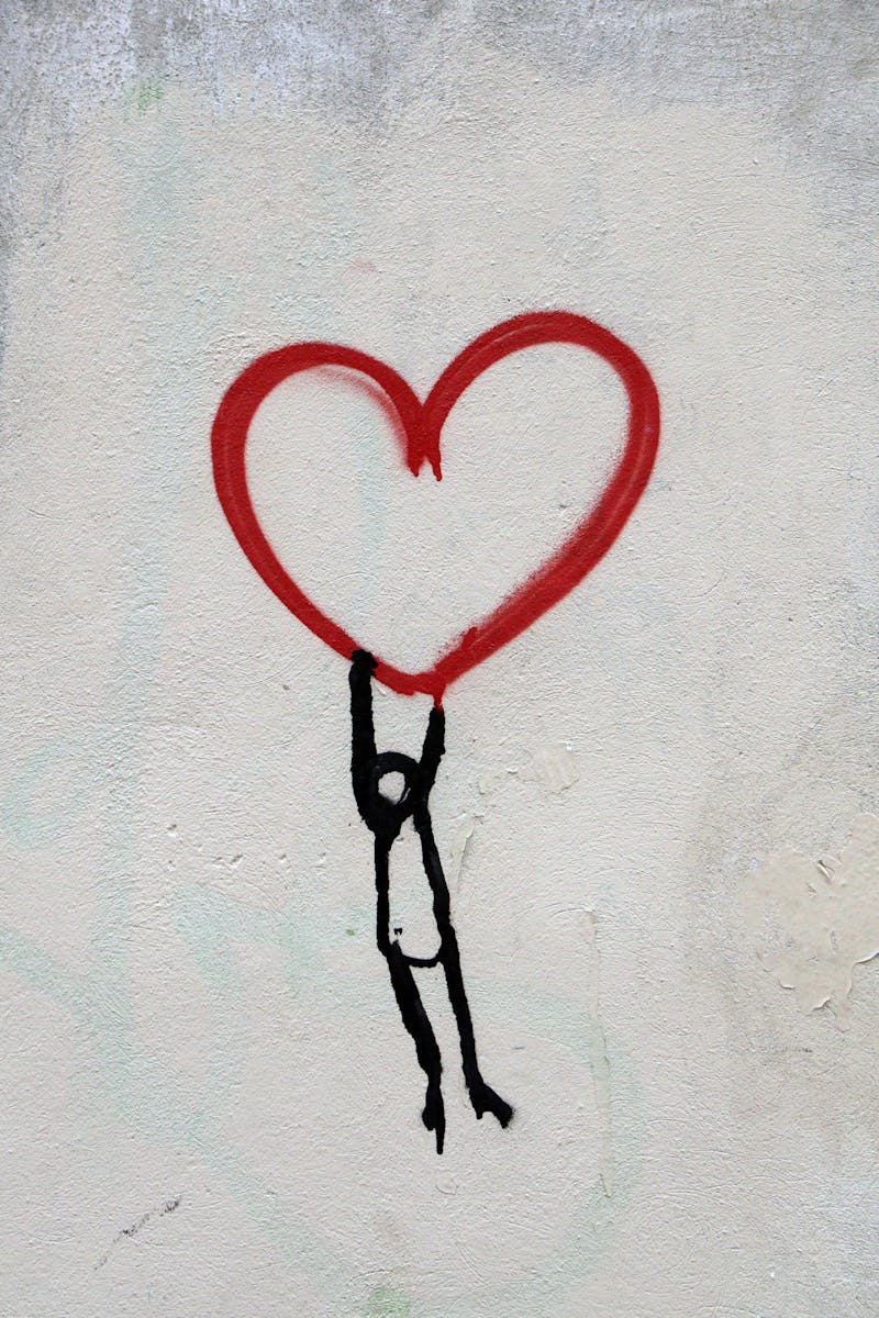 A stick figure hanging onto a heart.