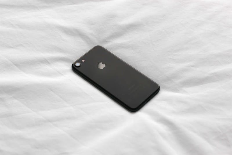 An iPhone laying on a bed.