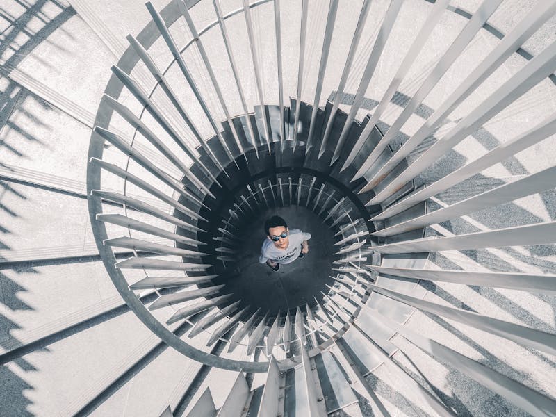 A white spiral staircase with a man at the bottom looking up