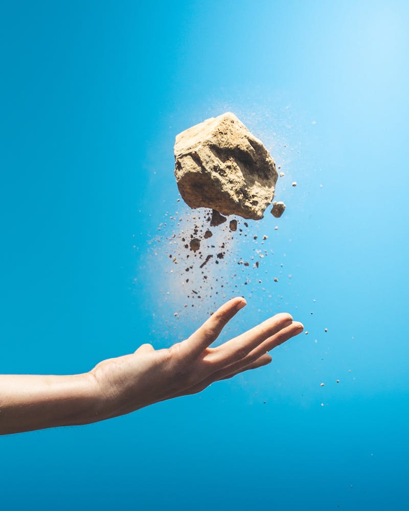 A hand throwing a clump of sand with a blue sky in the backgrownd