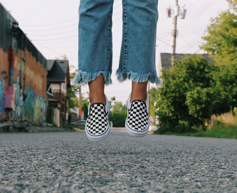 a person wearing jeans with tackies on jumping up in the air on the road