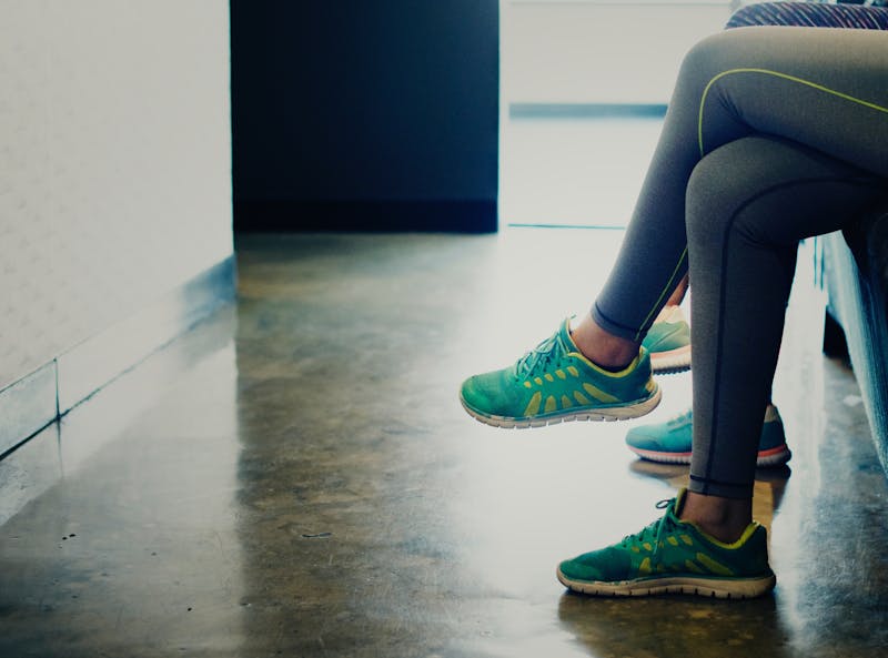 two girls sitting in running shoes and leggings.  You can only see their legs