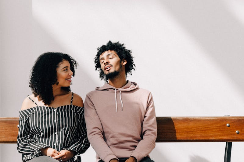 Two people talking on a bench.