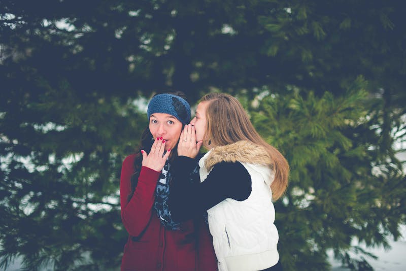 A girl whispering into another girls ear.