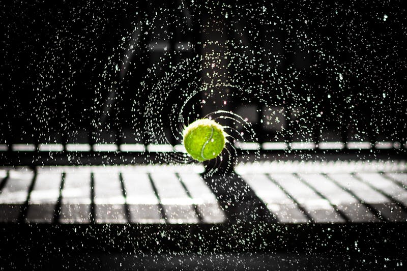 A wet tennis ball in mid-air.