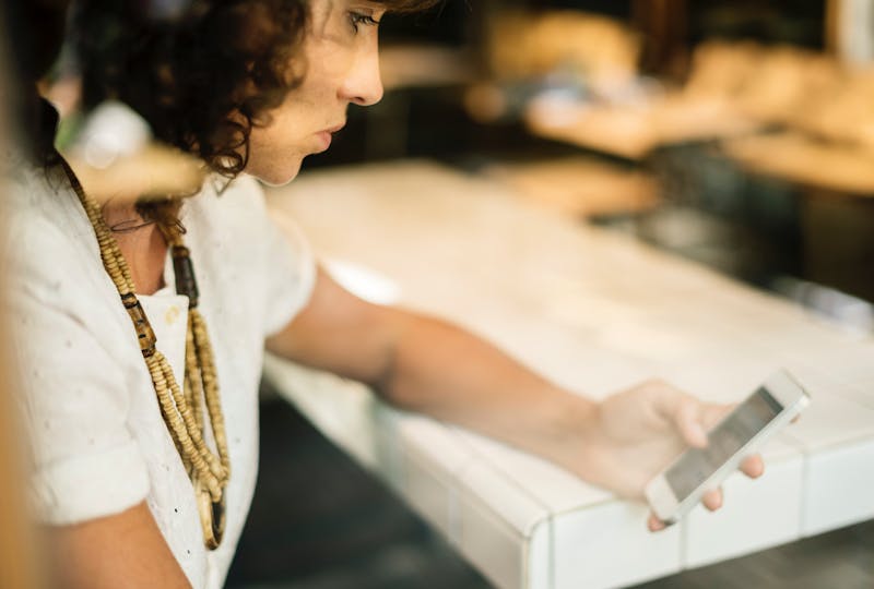 Woman sitting, looking at her phone.