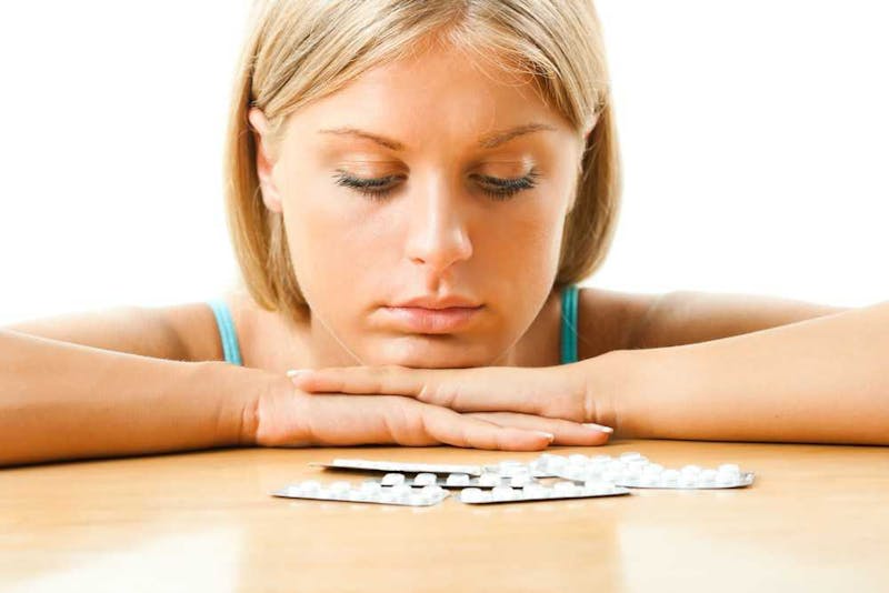 Woman staring at pills.