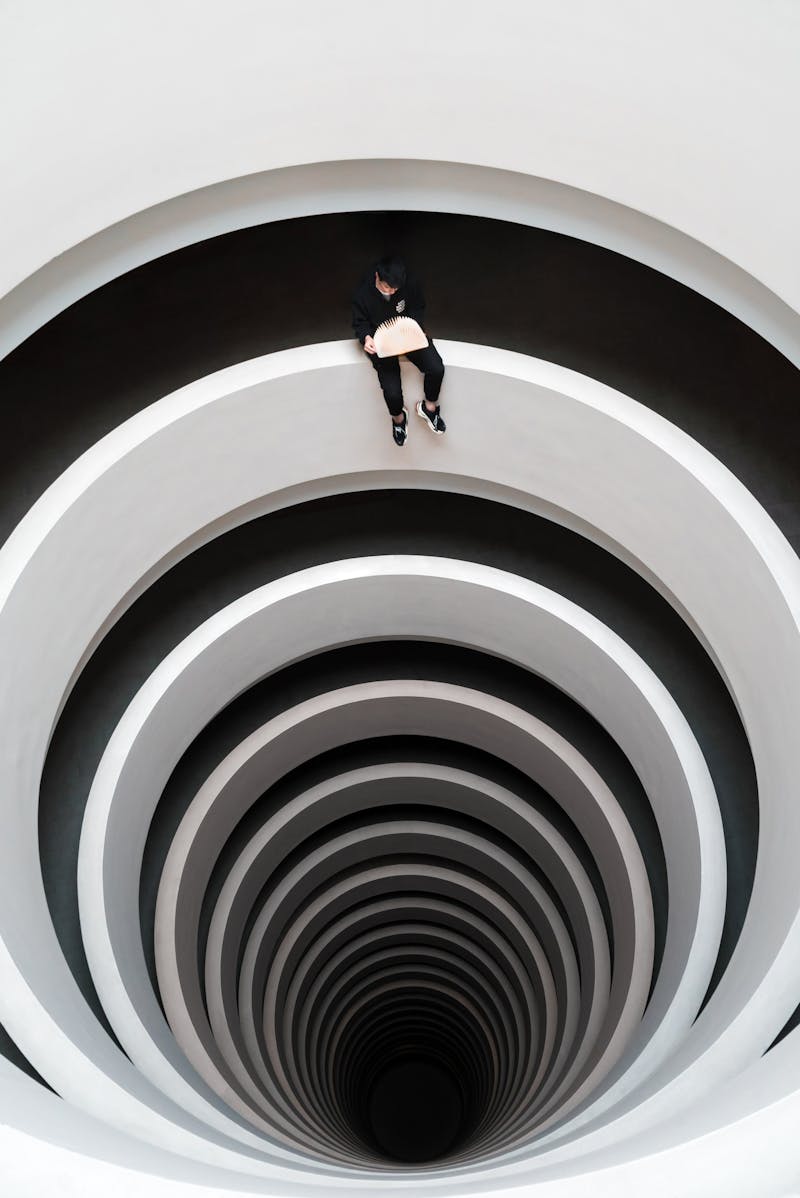 a black and white picture with a man sitting at the very top looking down a spiral